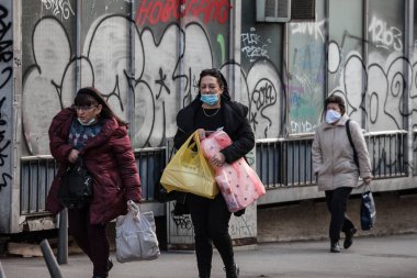 BELGRAD, SERBIA - 6 Mart 2021: Kadınlar için seçici bulanıklık, Coronavirus Covid 19 krizinde yüz maskesi koruyucu ekipman takan alışveriş ve market poşetleri taşıyarak yürümek