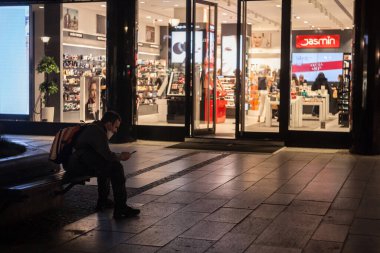 BELGRAD, SERBIA - 1 Nisan 2021: Coronavirus covid 19 sağlık krizi sırasında Belgrad 'ın bir caddesinde solunum maskesi takan ve akıllı telefonundaki uygulamaları kontrol eden bir adamın seçici bulanıklığı