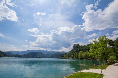 BLED, SLOVENIA - 12 Haziran 2021: Bled Gölü 'nün Panorama' sı, Blejsko Jezero, şatosu Blejski Hrad, güneşli bir yaz boyunca. Bled Castle Slovenya 'nın büyük bir anıtı
