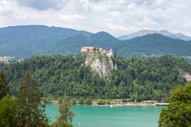 Bled Gölü 'nün Panorama' sı Blejsko Jezero, şatosu Blejski Hrad ile birlikte Julian Alpleri 'nin dağlarıyla dolu bulutlu bir yaz boyunca. Bled Castle Slovenya 'nın büyük bir anıtı