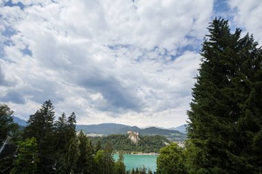 Bled Gölü 'nün Panorama' sı Blejsko Jezero, şatosu Blejski Hrad ile birlikte Julian Alpleri 'nin dağlarıyla dolu bulutlu bir yaz boyunca. Bled Castle Slovenya 'nın büyük bir anıtı