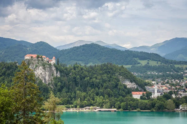 Bled Gölü 'nün Panorama' sı Blejsko Jezero, şatosu Blejski Hrad ile birlikte Julian Alpleri 'nin dağlarıyla dolu bulutlu bir yaz boyunca. Bled Castle Slovenya 'nın büyük bir anıtı