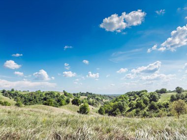 Sırbistan 'ın Voyvodina kentindeki Zagajicka Brda' nın geniş panoraması - Deliblatska Kumları bölgesinin çayırlık tepelerini, dağınık mavi bulutların altında, bahar aylarında bozkırları gösteren.