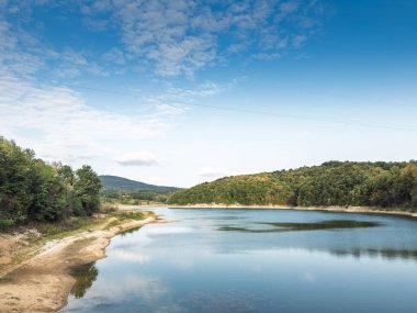 Garasko Jezero, Garas Gölü, Sırbistan Arandjelovac yakınlarında. Ormanlık tepelerin, kumlu kıyıların ve yüksek mavi gökyüzünün yanında sakin bir kırsal su manzarası olan Sırp doğasının sembolü olan sakin bir göl..