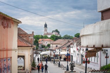 GROCKA, SERBIA - 25 Mayıs 2025: Belgrad 'ın Grocka kentindeki Bulevar Oslobodjenja, yaya çekirdeği, sokak saati, kilise, eski evlerin önünden geçen insanlar. grocka Belgrad 'ın bir banliyösü.
