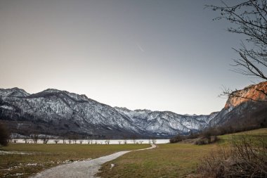 Slovenya 'daki Bohinjsko jezero' nun üzerine çöküş. Julian Alpleri 'nde kar yağarken dolambaçlı bir yol Bohinj Gölü' ne çıkar. Sakin su ve solgun bir akşam gökyüzü açık çayırlar tarafından çerçevelenmiş huzurlu bir kış manzarası yaratır..