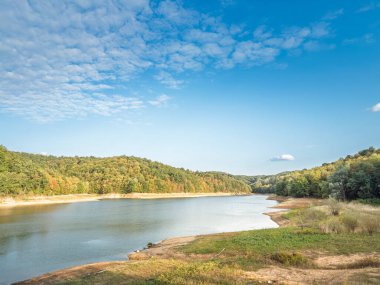 Sırbistan 'ın Arandjelovac kenti yakınlarındaki Garasko Jezero' nun geniş görüşü. Baraj gölü, açık kıyı şeridi ve berrak gökyüzü altındaki sakin su ile ormanlık tepeler arasında kıvrımlar oluşturarak, huzurlu bir kırsal alanı gösteriyor..