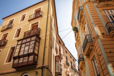 Valencia, İspanya 'nın eski bir kasabası olan Ciutat Vella' daki konut binalarına bakıyorum. Renkli cepheleri, balkonları ve kapalı körfez pencereleri dar bir sokakta öğleden sonra güneşiyle aydınlatılıyor..
