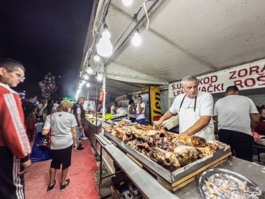 SABAC, SERBIA - SEPTEMBER 20, 2025: Bir satıcı, Sırbistan 'da Sabacki Vasar Fuarı sırasında, Balkan ve Sırp mutfağının bir simgesi olan yoğun bir gıda standında ceviz dilimliyor.