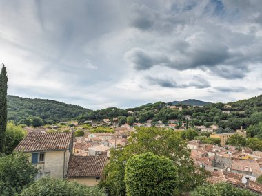 Var, Provence 'de köklü bir köy olan Collobrieres' in yüksek manzaralı çatıları, dramatik bulutların altında Maures tepeleri arasında yer alıyor. Evler tipik bir Provence yerleşimini gösteriyor..
