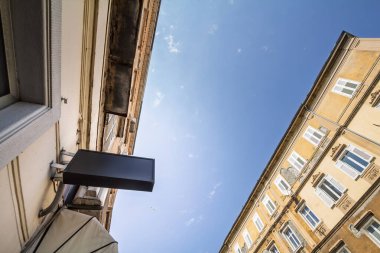 Avrupa caddesinin üzerine asılmış boş dikdörtgen siyah tabela temiz fotokopi alanı sunuyor. Minimalist panel klasik cephelere ve açık gökyüzüne karşı duruyor, markalaşmaya ya da yol bulma kavramlarına hazır..