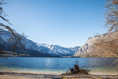 Bohinjsko jezero 'dan Julian Alpleri' nin karla kaplı tepelerine doğru yayılmış bir manzara. Sakin su ve berrak gökyüzü Slovenya Triglav Ulusal Parkı 'ndaki Bohinj Gölü' nün Alp karakterini aktarıyor.