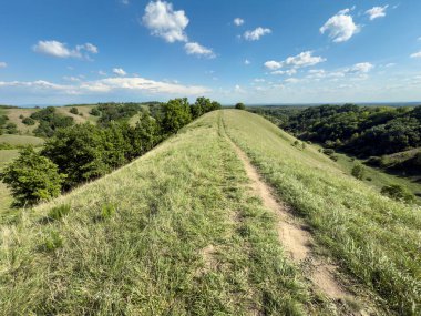 Sırbistan 'ın Voyvodina kentindeki Banat kentindeki Zagajicka Brda' nın panoramik manzarası, eşsiz jeomorfoloji ve yürüyüş manzarasında, kayan kayalık tepeler ve yeşil vadilerin üzerinde yeşil bir tepe yolu gösteriyor.