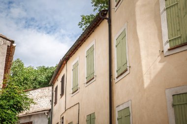 Collobrieres, Fransa 'daki tipik Provencal köy evleri cephesi. Pastel duvarları ve yeşil kepenkleri var. Kompozisyon, Fransız emlak karakteri ve Akdeniz dilsel mimarisini gösteriyor
