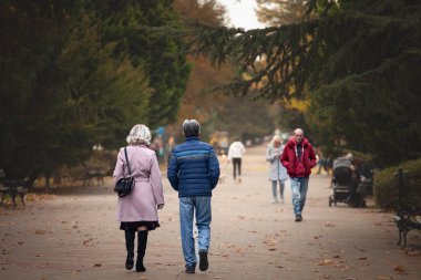 SUBOTICA, SERBIA - 16 Kasım 2025: Subotica 'da yaya yolu boyunca birlikte yürüyen orta yaşlı çift. Sahne günlük hayatı, arkadaşlığı ve rahat açık hava hareketlerini gösteriyor..