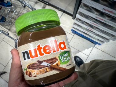 BELGRAD, SERBIA - 11 Ekim 2025: Süpermarket koridorunda yeşil kapaklı bitki bazlı Nutella. Etikette vejetaryen sertifikası ve klasik fındık sertifikası vurgulanıyor.
