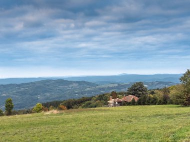 Sırbistan 'ın Vrh Rajac kentinden geniş bir manzara, küçük bir kır evi ve katmanlı tepeler, popüler bir yürüyüş manzarası. Rajac bir Sumadija dağıdır, dinarik Alplerin bir parçası, Sırp turistik beldesi.