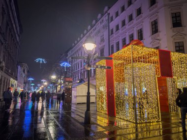 BELGRAD, SERBIA - 7 Aralık 2025: Yayalar, Belgrad 'ın Kneza Mihailova caddesinde büyük aydınlatılmış bir Noel süslemesinin önünden yeni yıl ve gece yılbaşı süsleriyle geçiyorlar.