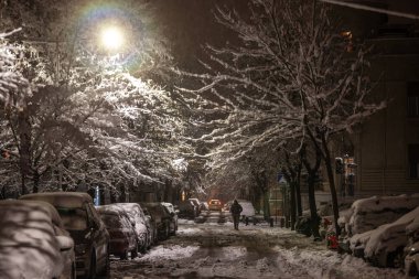 BELGRAD, SERBIA - 4 HAZİRAN 2026: Geceleri Dorcol, Belgrad, Sırbistan 'da kar yağışlı kar yağışı, kışın buzlu bir iskan caddesinde yürüyen yayalar gibi araçlar ve ağaçlarla kaplı.