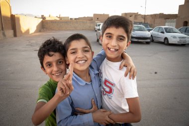 YAZD, İRAN - 9 AĞUSTOS 2016: İran 'da gülümseyen ve kucaklaşan üç İranlı çocuk, çocukluk ve gençlik kültürü sosyal bağları üzerine dostane bir portre için poz vererek İranlı yeni nesil.