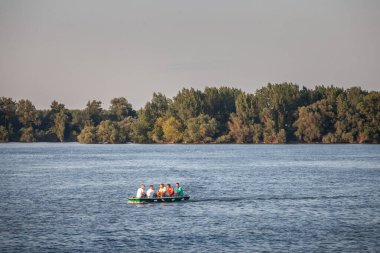 BELGRAD, SERBIA - 2 AĞUSTOS 2025: Sırbistan 'ın Zemun kenti yakınlarındaki Tuna Nehri' ni geçen küçük bir motorlu tekne üzerindeki arkadaşlar.