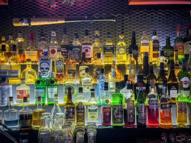 BELGRAD, SERBIA - 19 Aralık 2025: Belgrad, Sırbistan 'da bir gece barında içki ve alkolle dolu raflar, kokteyller, karışık içecekler, gece hayatı servisi için viski, cin, rom ve aperatif şişeleri.