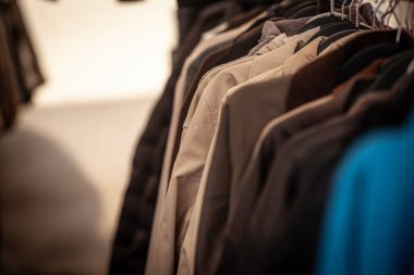 İkinci el ceketlerin ucuzluk mağazasındaki askılara yakından bakılması, hızlı modaya alternatif olarak yeniden kullanım ve yeniden satış giysilerinin, sürdürülebilir alışverişin ve dairesel ekonominin altını çizilmesi.