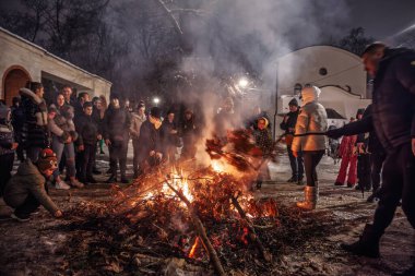 BELGRAD, SERBIA - 6 Ocak 2026: İnsanlar, Belgrad 'daki bir kilisenin yakınında, Sırp Ortodoks Noel Arifesi geleneği Badnjak sırasında bir şenlik ateşi etrafında toplanarak, kıvılcımların yükselmesiyle ısınıyor.