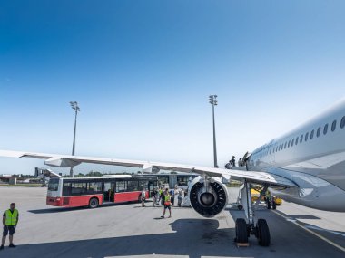 MUNİH, GERMANY - 21 Haziran 2025: Yolcular Münih Havalimanı 'ndaki pistte bir Lufthansa uçağına biniyor, yakınlarda havaalanı operasyonlarını, seyahat ve ticari havacılık faaliyetlerini gösteren otobüsler ve ekipmanlar bulunuyor.