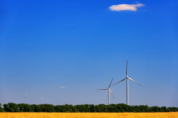 Ветряная турбина на фоне поля и голубого неба — стоковое фото