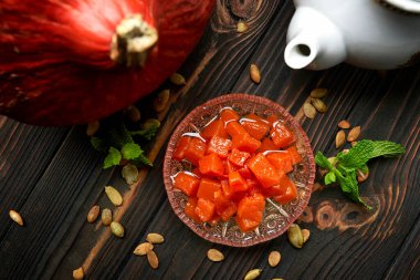 Kabak reçeli, koyu ahşap bir zemin üzerinde, balkabağı, nane ve kabak tohumlarıyla