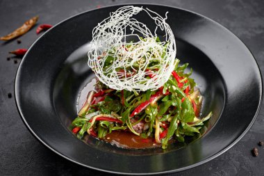 Sebze salatası, roka, dolma biber, salatalık ve keten tohumu, siyah arka planda.