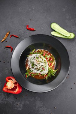 Sebze salatası, roka, dolma biber, salatalık ve keten tohumu, siyah arka planda.