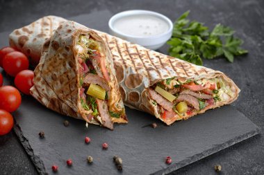 Shawarma ile et, kesme, sos, domates, peynir, otlar ve sarımsak, siyah bir arkaplanda