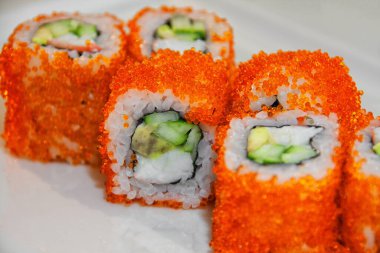 Suşi, balık, havyar, kremalı sos, avokado, beyaz tabakta.