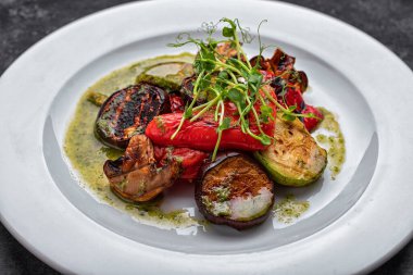 Mantarlı ızgara sebzeler, kabak, patlıcan, dolma biber, mantar, soslu beyaz bir tabakta.