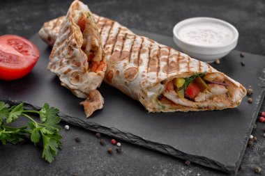 Shawarma ile et, kesme, sos, domates, peynir, otlar ve sarımsak, siyah bir arkaplanda
