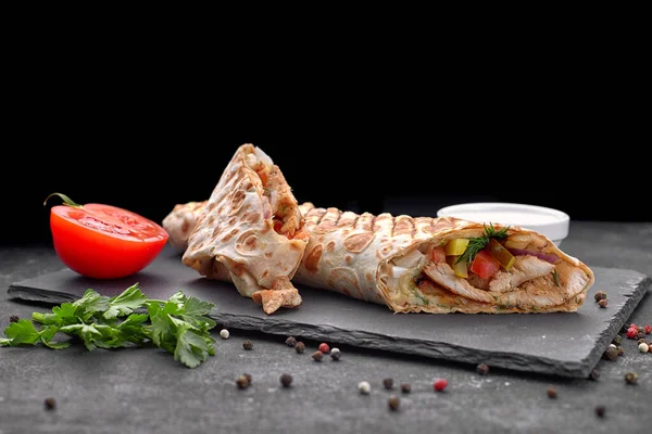 Shawarma ile et, kesme, sos, domates, peynir, otlar ve sarımsak, siyah bir arkaplanda