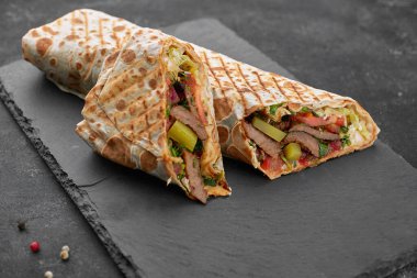 Shawarma ile et, kesme, sos, domates, peynir, otlar ve sarımsak, siyah bir arkaplanda