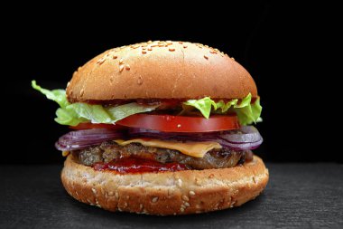 Hamburger, çizburger, hamburger et pirzolası, peynir, marul ve domates, siyah arkaplanda.