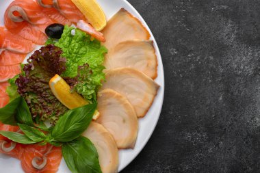 Balık, ince dilimlenmiş, escolar, tereyağlı, somon, fesleğen ve marullu beyaz bir tabakta, koyu bir arka planda.