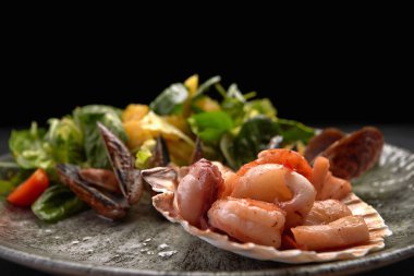Seafood salad with pineapple and oranges on a plate, on a dark background