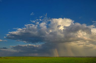Yeşil buğday tarlasının üzerinde gökkuşağı olan yağmur bulutları. Yatay yönelim, alanın sığ derinliği