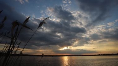 Gölde gün batımı, bulutlar ve yansımalarla dolu bir nehir.