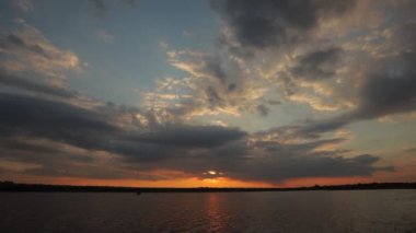 Gölde gün batımı, bulutlar ve yansımalarla dolu bir nehir.