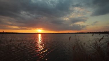 Gölde gün batımı, bulutlar ve yansımalarla dolu bir nehir.