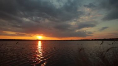 Gölde gün batımı, bulutlar ve yansımalarla dolu bir nehir.