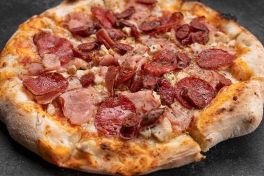 Koyu beton arka planda dört etli pizza.