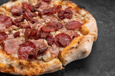 Koyu beton arka planda dört etli pizza.