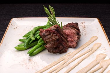 Filet mignon with asparagus on a light plate, on a dark background